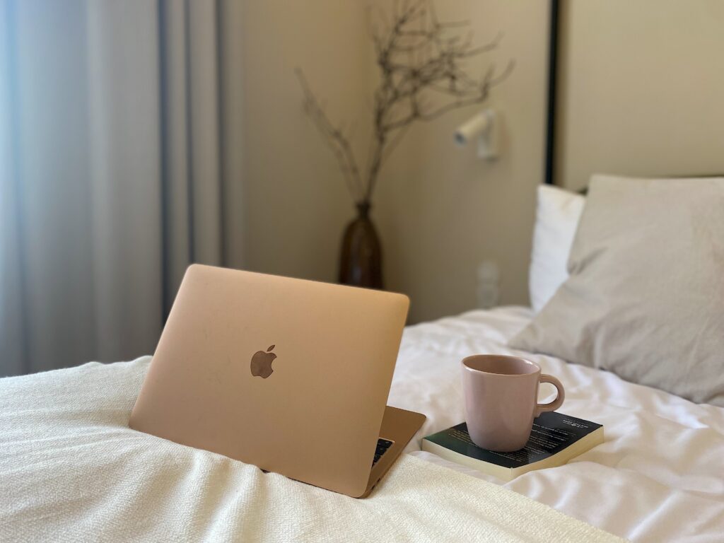 Utdrag fra et hotellrom ved Dwór Uphagena, et hotell i Gdansk. Bildet viser en mac, bok og tekopp i sengen.